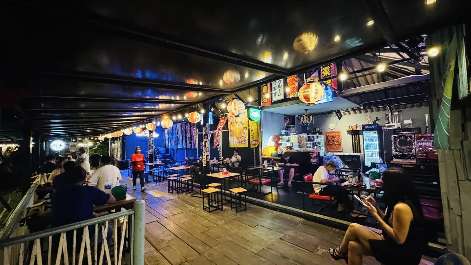 บรรยากาศร้าน Mara Station ยามค่ำ — โคมไฟกระดาษญี่ปุ่นและป้ายไฟ Asahi เหนือโต๊ะลูกค้า